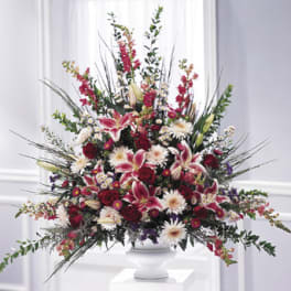 Large mixed floral arrangement in a white pedestal vase