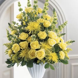 Yellow roses and spider mums arranged in a white vase