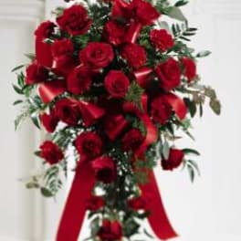 Red rose standing spray with a red ribbon on a white easel