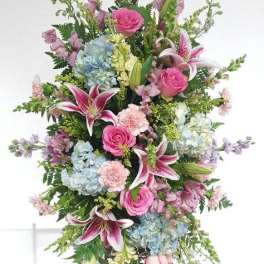 Standing spray of pink and blue flowers with lilies and roses