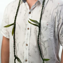 Braided green leaf lei draped over a patterned white shirt
