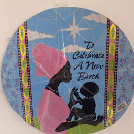 Round decorative sign with silhouettes and the words "To Celebrate A New Birth"