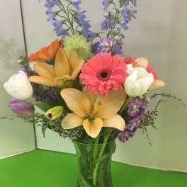 Mixed bouquet in a clear glass vase with lilies, gerbera daisies, and tulips