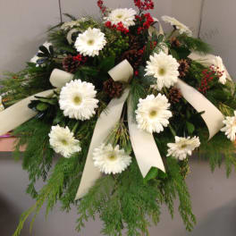 White gerbera daisies with red berries and cream ribbons in a low arrangement