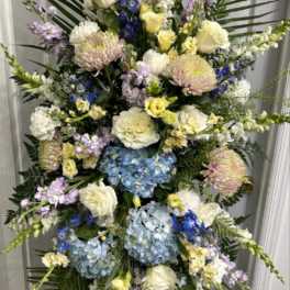 Tall standing floral spray with blue hydrangeas, white roses, and pastel blooms