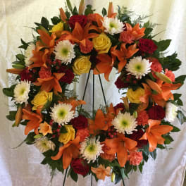 Heart-shaped floral wreath with orange lilies, roses, and white mums