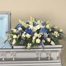 White and blue floral spray arranged on a silver casket