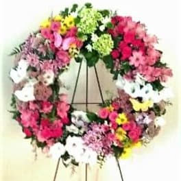 Colorful floral wreath on a stand with pink, white, yellow, and green blooms
