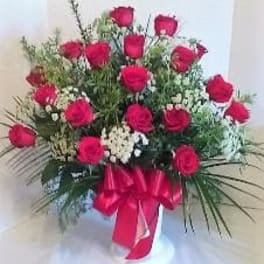 Bouquet of red roses with white filler flowers in a vase, tied with a red ribbon
