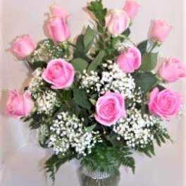 Pink roses arranged in a clear glass vase with white filler flowers