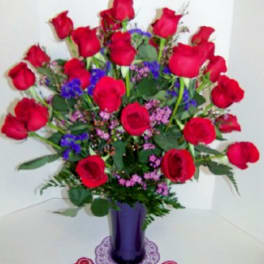 Bouquet of red roses in a purple vase with small purple accents