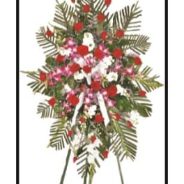 Standing floral spray with red, white, and pink flowers on a tripod easel