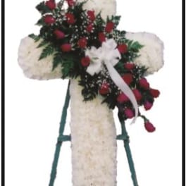White floral cross on a stand with red roses and a white ribbon