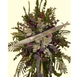 Standing floral spray with white ribbon and mixed purple, pink, and white flowers