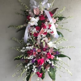 Tall standing floral spray with pink, white, and purple flowers on an easel