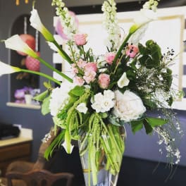 Tall floral arrangement with white calla lilies and pink roses in a glass vase