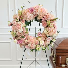 Pastel floral wreath on a stand with pink and cream blooms