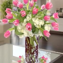 Pink tulips arranged with white hydrangeas in a clear glass vase