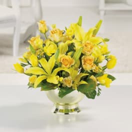 Low yellow lily and rose arrangement in a pale gold pedestal bowl