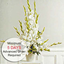 Tall arrangement of white flowers with long spikes in a white urn-style vase