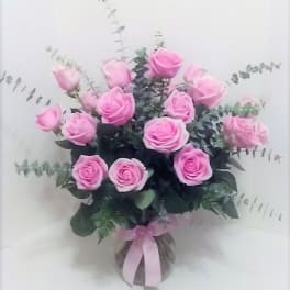Pink roses arranged in a clear vase with eucalyptus foliage