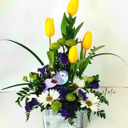 Yellow tulips with white daisies and purple filler in a silver container