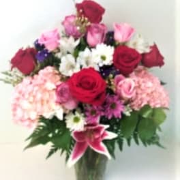 Mixed bouquet of roses, lilies, and daisies in a glass vase