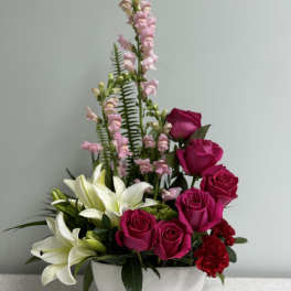 Pink roses and white lilies arranged in a white bowl vase