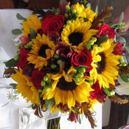 Bouquet of sunflowers and red roses with green berries