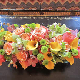 Low floral centerpiece with roses and calla lilies on a dark tray