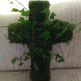 Moss-covered cross with trailing ivy on a patterned sofa