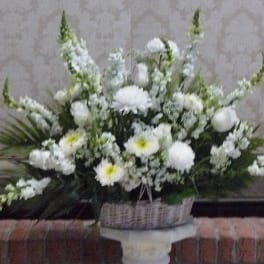 White floral arrangement in a woven basket on a pedestal