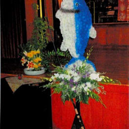 Large blue-and-white floral dolphin display on a stand with a flower arrangement at the base