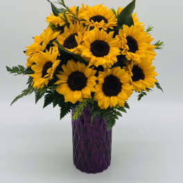Bouquet of yellow sunflowers in a purple vase