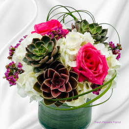 Pink roses and white hydrangeas with succulents in a glass vase