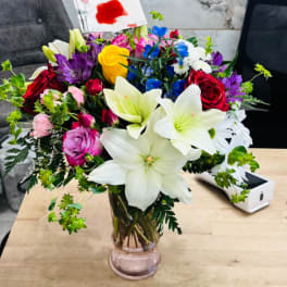 Mixed bouquet of lilies, roses, and daisies in a glass vase