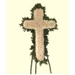 Cross-shaped floral funeral tribute with pale flowers and dark greenery
