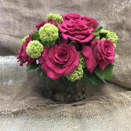 Pink roses with green pom-pom flowers in a glass vase