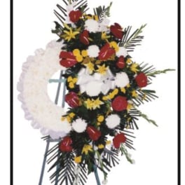 Standing floral wreath with red, white, and yellow flowers on an easel