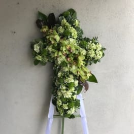 Cross-shaped floral spray with green flowers on a stand