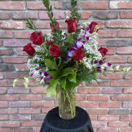 Red roses and purple orchids in a glass vase