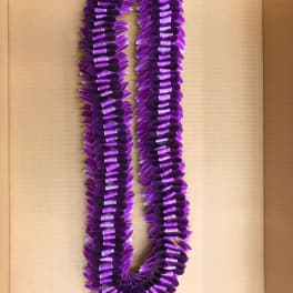 Purple lei made of layered petals on a cardboard background