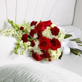 Red roses and white flowers arranged in a bouquet on a white chair