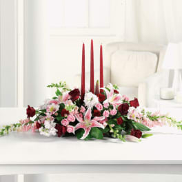 Low floral centerpiece with red candles and pink lilies and roses