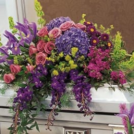 Colorful casket spray with pink roses and purple flowers