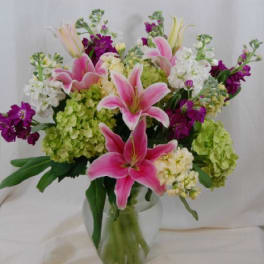 Pink lilies and mixed blooms in a clear glass vase