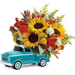 Bouquet of sunflowers and red roses in a turquoise toy truck