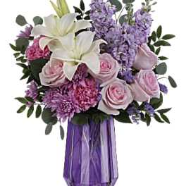 Bouquet of white lilies, pink roses, and purple flowers in a purple vase