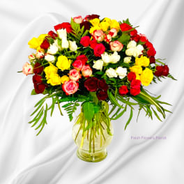 Mixed roses in red, white, pink, and yellow in a glass vase
