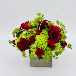 Red roses and green hydrangeas in a square gray container